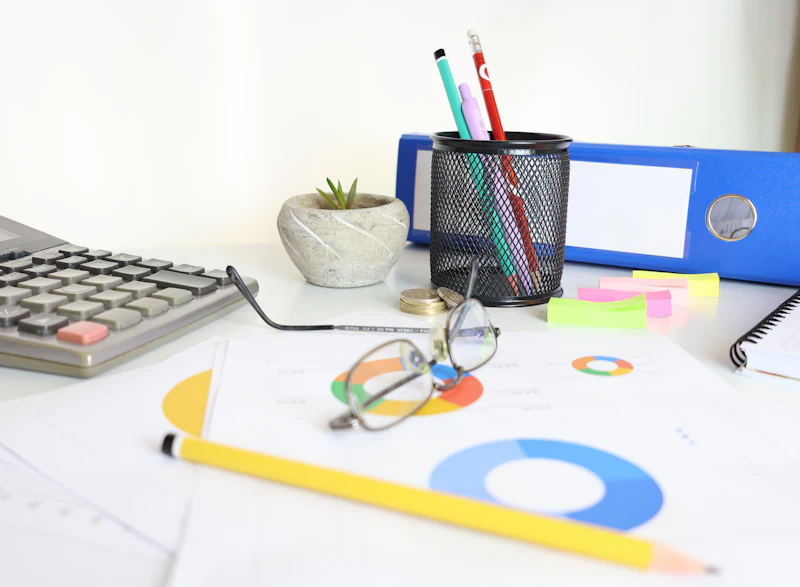 A desk with a calculator, notes and charts